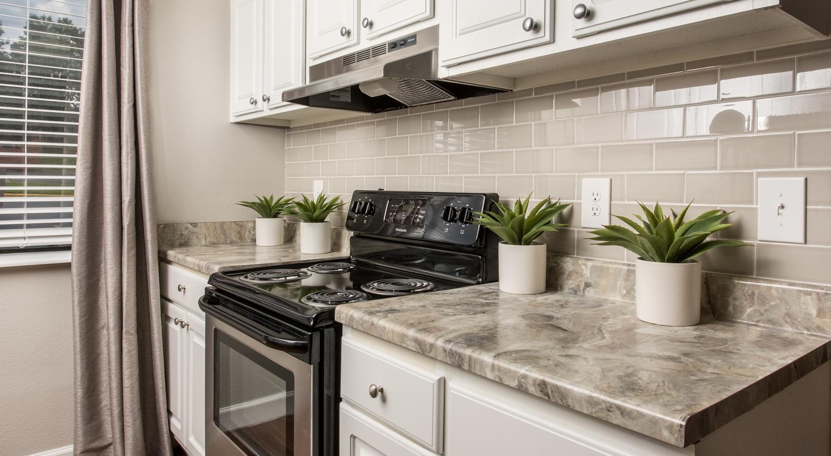 Beautiful kitchens with designer finishes a kitchen with white cabinets a stovetop and a window