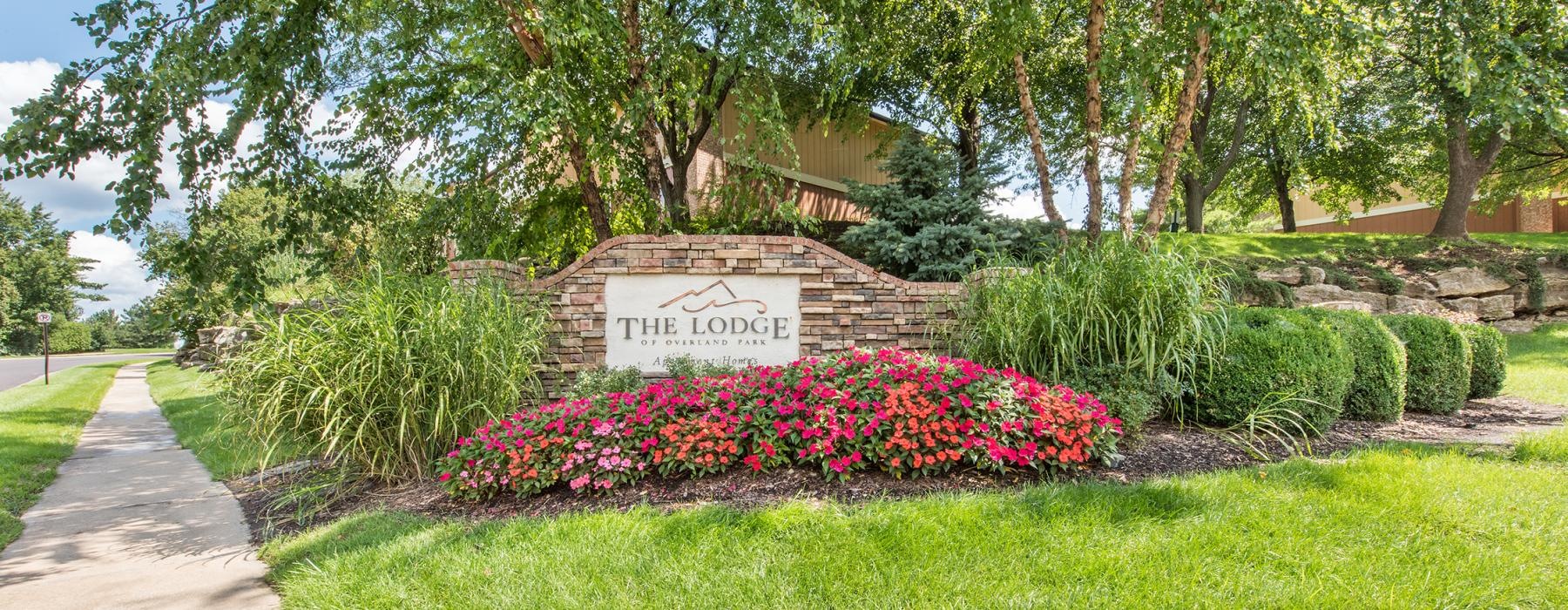 a sign in a garden that reads the lodge