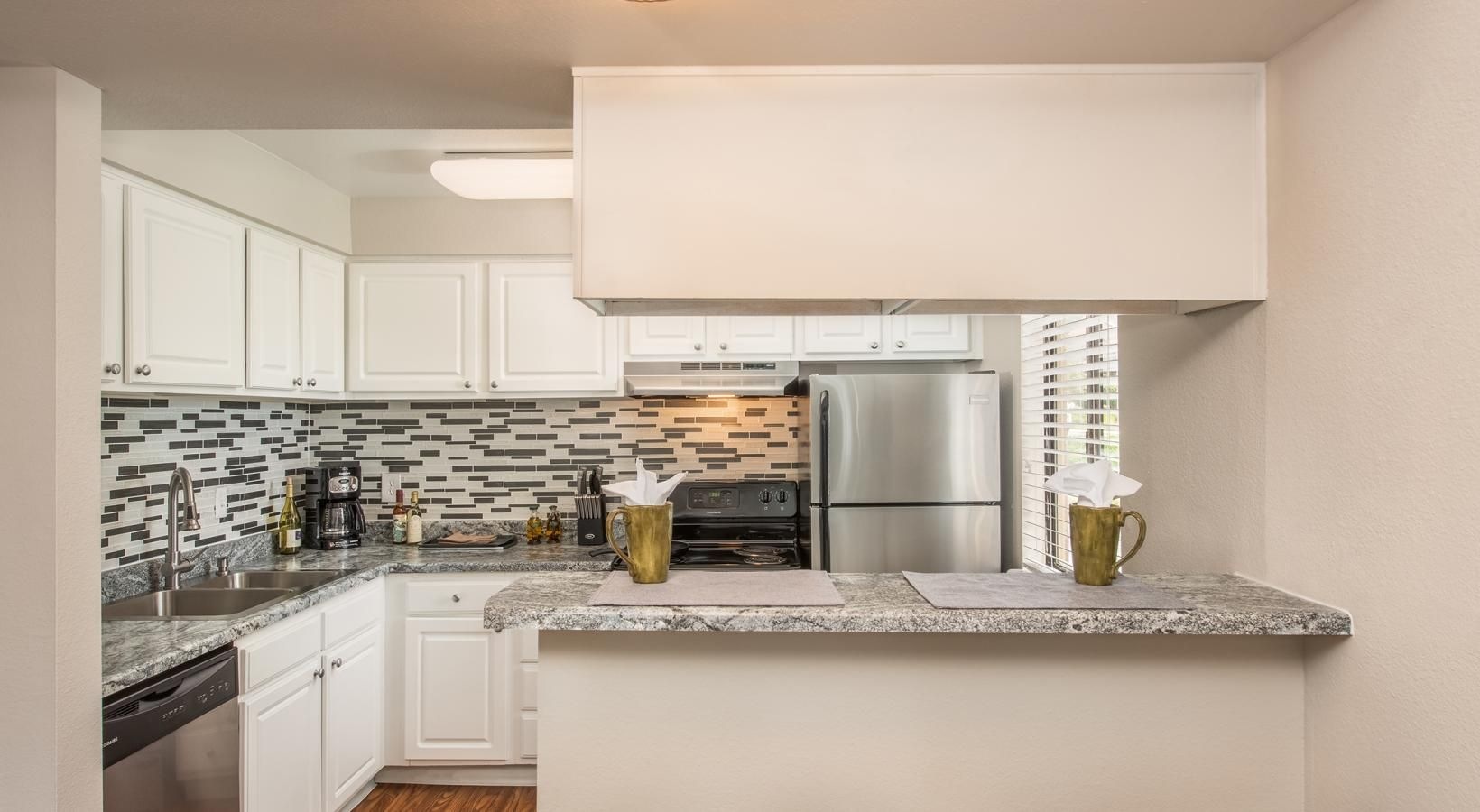 Generous living spaces to relax and unwind a kitchen with white cabinets and a breakfast bar
