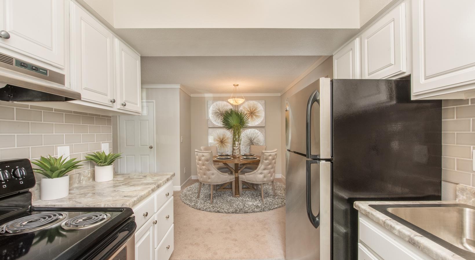 Beautiful kitchens with designer finishes a kitchen with white cabinets a stovetop a fridge and a sink